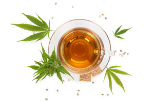 Cannabis tea with crackers from above with cannabis plant and leaves isolated on white background. Alternative medicine medical cannabis natural remedy.